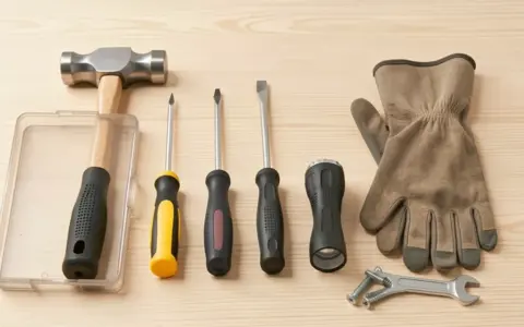 Plain hand tools and work gloves arranged on a wooden surface