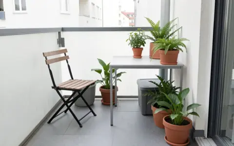 Small balcony with a folding chair, narrow table, and potted plants